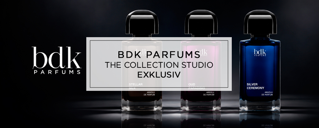 Drei elegante Parfumflakons von BDK Parfums stehen nebeneinander vor dunklem Hintergrund, stilvoll ausgeleuchtet mit Spiegelungen und dem Logo links daneben.