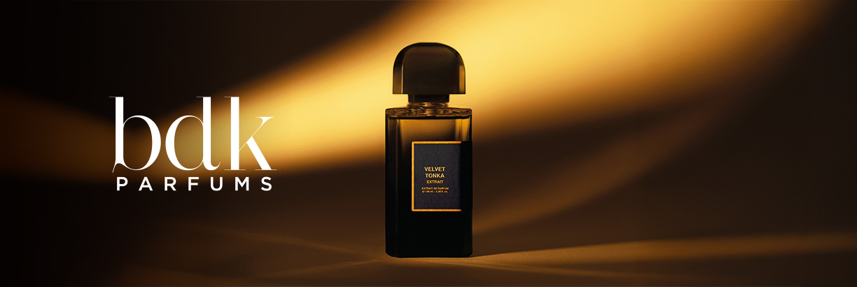 Schwarzer Flakon des Parfums Velvet Tonka von bdk Parfums vor einem dunkelbraunen Hintergrund mit warmen, goldenen Lichtstrahlen.