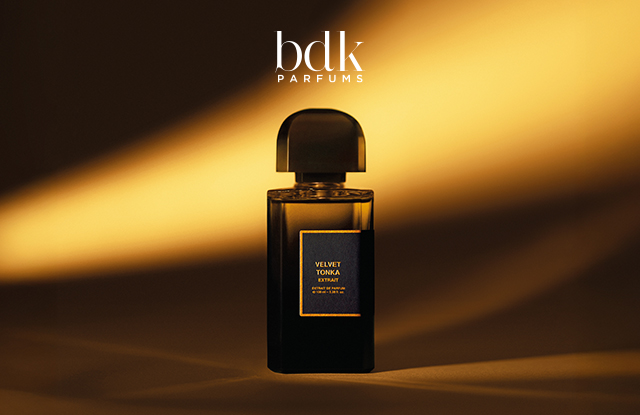 Schwarzer Flakon des Parfums Velvet Tonka von bdk Parfums vor einem dunkelbraunen Hintergrund mit warmen, goldenen Lichtstrahlen.