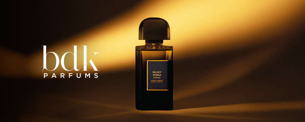 Schwarzer Flakon des Parfums Velvet Tonka von bdk Parfums vor einem dunkelbraunen Hintergrund mit warmen, goldenen Lichtstrahlen.