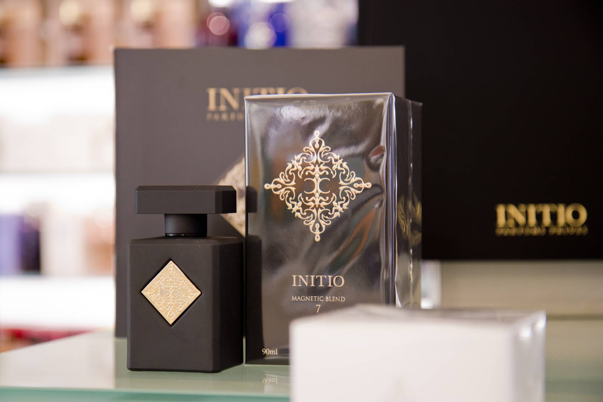 Schwarzer Parfumflakon Initio Magnetic Blend 7 mit goldfarbenem Ornament, daneben die passende schwarze Verpackung