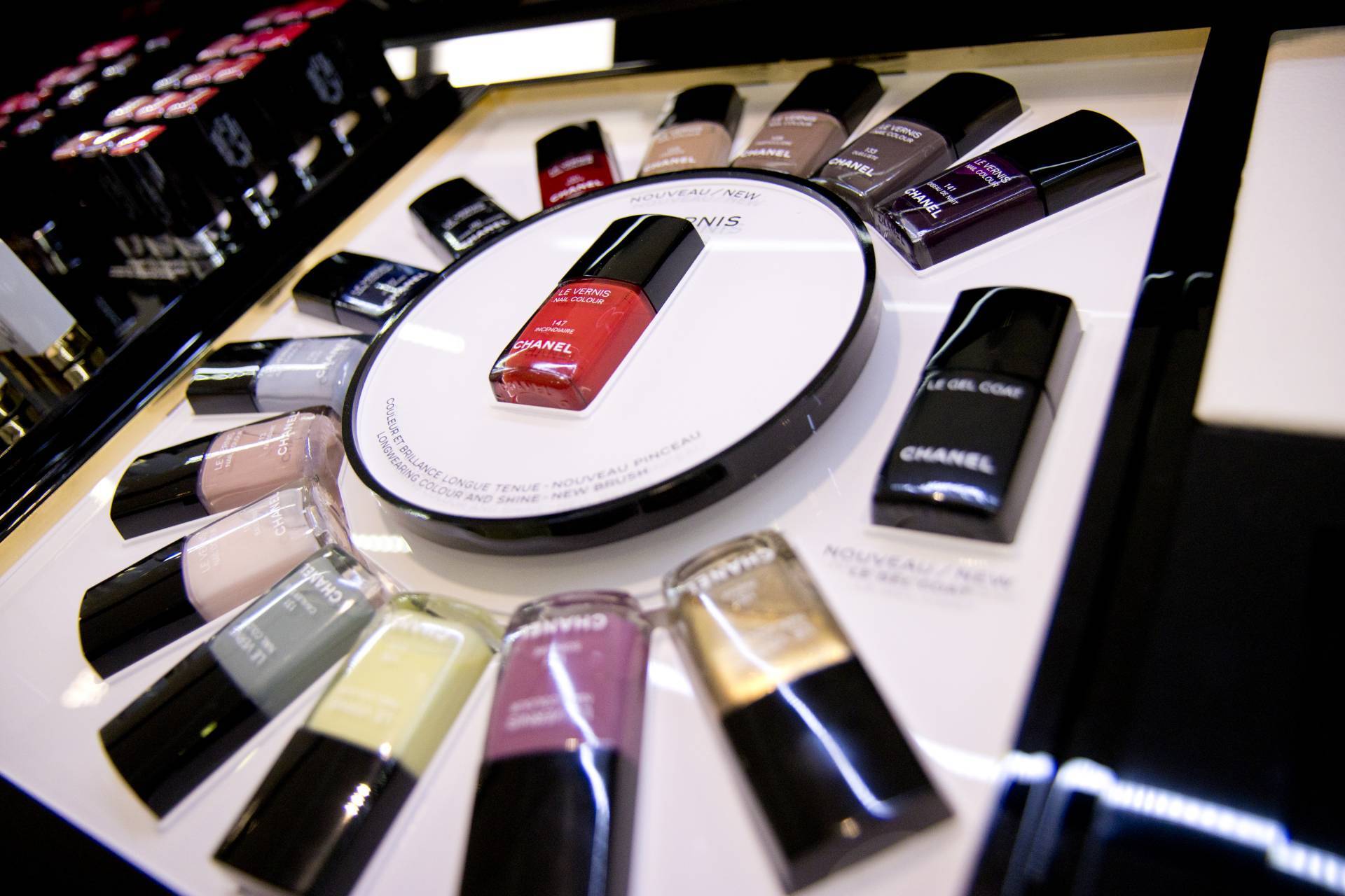 Chanel Nagellacke in verschiedenen Farben, kreisförmig auf einem beleuchteten Display präsentiert, roter Nagellack im Mittelpunkt