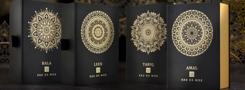 Schwarze Parfumverpackungen von Eau de Moe mit goldenen ornamentalen Mustern und Produktnamen Hala, Leen, Tariq und Amal