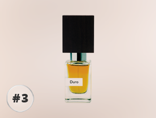 Nasomatto Duro Parfumflakon aus klarem Glas mit goldfarbenem Duft und schwarzem, kantigem Holzverschluss vor hellem Hintergrund