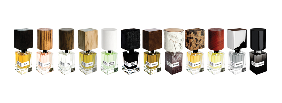 Übersicht mehrerer Nasomatto Parfumflakons in einer Reihe mit unterschiedlichen Holzverschlüssen und Duftfarben vor weißem Hintergrund