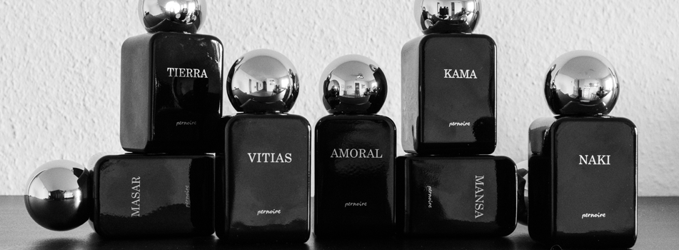 Schwarze Pernoire Parfumflakons mit silbernen Kugelverschlüssen, angeordnet als Gruppe vor hellem Hintergrund