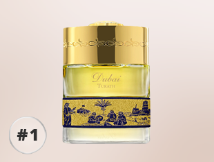 Parfumflakon The Spirit of Dubai Turath mit goldenem Verschluss, gelbem Duft und blau-goldenem Zierband mit orientalischem Motiv, freigestellt vor hellem Hintergrund.