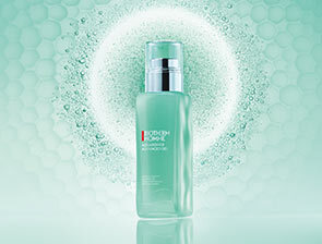 Ein Feuchtigkeitspflege-Produkt von Biotherm Homme in einer türkisfarbenen Flasche steht vor einem strukturierten, mintgrünen Hintergrund mit Lichtschein.