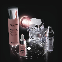Filorga Global-Repair Advanced Pflegeserie mit mehreren Produkten, darunter eine rosa Flasche mit silbernem Deckel, ein Serum mit Pipette sowie zwei Cremetiegel und ein weiterer Spender, arrangiert auf dunklem Hintergrund mit kreisförmigem Leuchteffekt.