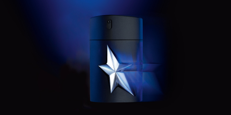 Dunkelblauer Parfumflakon von Mugler mit silbernem, leuchtendem Stern in der Mitte. Der Flakon steht vor einem schwarzen Hintergrund mit blauen Lichtreflexen und gehört zur Duftlinie 'A*Men'.