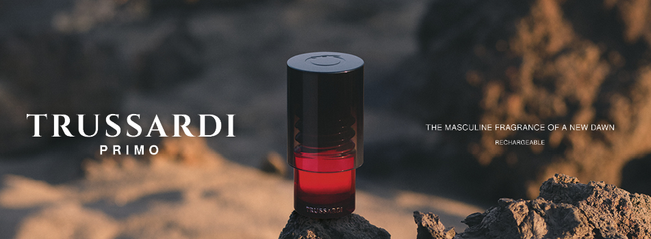 Werbung für das Herrenparfum 'Trussardi Primo': In der Mitte ein rot-schwarzer, zylindrischer Flakon auf felsigem Untergrund bei Sonnenuntergang. Links der weiße Schriftzug 'TRUSSARDI PRIMO', rechts der Slogan 'The masculine fragrance of a new dawn – rechargeable'.