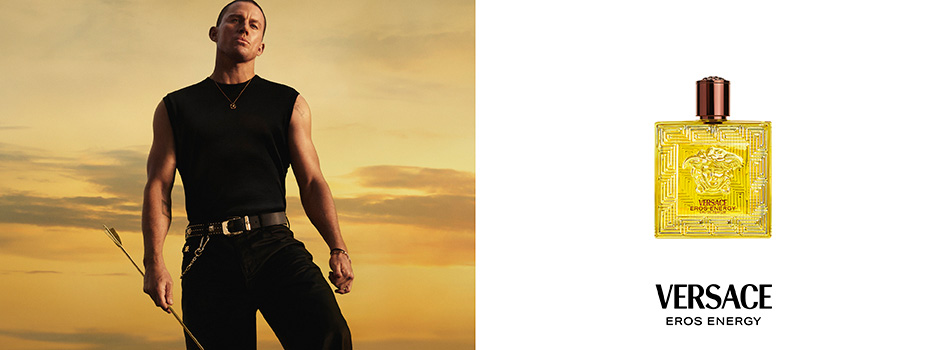 Werbebild für den Duft „Versace Eros Energy“: Links steht ein Mann mit kurzem Haar in schwarzem ärmellosem Shirt und schwarzer Hose vor einem goldgelben Sonnenuntergang, in der Hand hält er einen Pfeil. Rechts daneben ist der gelbe Parfumflakon mit Reliefmuster und Medusa-Kopf zu sehen, darunter das Versace-Logo mit der Aufschrift „Eros Energy“.