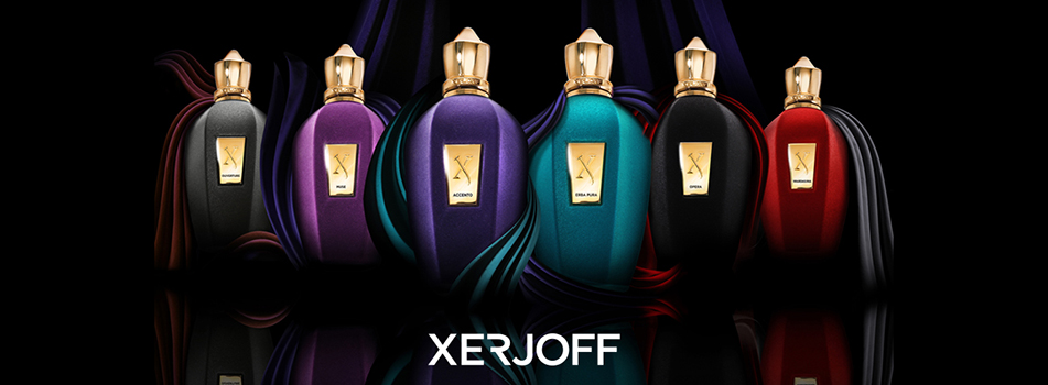 Werbeanzeige für die Luxus-Parfümmarke Xerjoff. Sechs elegante Parfümflakons in verschiedenen Farben – Schwarz, Violett, Lila, Türkis, Dunkelblau und Rot – stehen nebeneinander auf schwarzem Hintergrund mit Lichtreflexionen. Jeder Flakon hat einen goldenen Verschluss und ein goldenes Etikett mit dem Xerjoff-Logo. Unten im Bild steht der Markenname 'Xerjoff' in weißer Schrift.