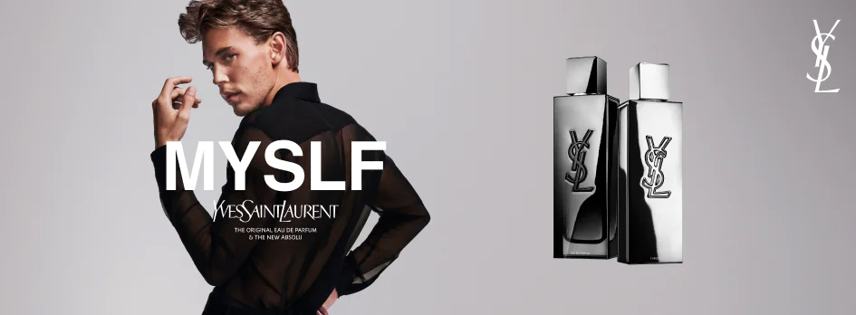 Werbeanzeige für das Parfum 'MYSLF' von Yves Saint Laurent. Links steht ein junger Mann mit gewelltem Haar, der in die Kamera blickt. Er trägt ein schwarzes, durchsichtiges Oberteil. Vor ihm steht der Schriftzug 'MYSLF' und darunter das Yves-Saint-Laurent-Logo mit dem Text 'The Original Eau de Parfum & the New Absolu'. Rechts im Bild zwei silberne Parfumflakons mit reflektierender Oberfläche und dem YSL-Logo. Im Hintergrund ein neutraler grauer Farbverlauf.